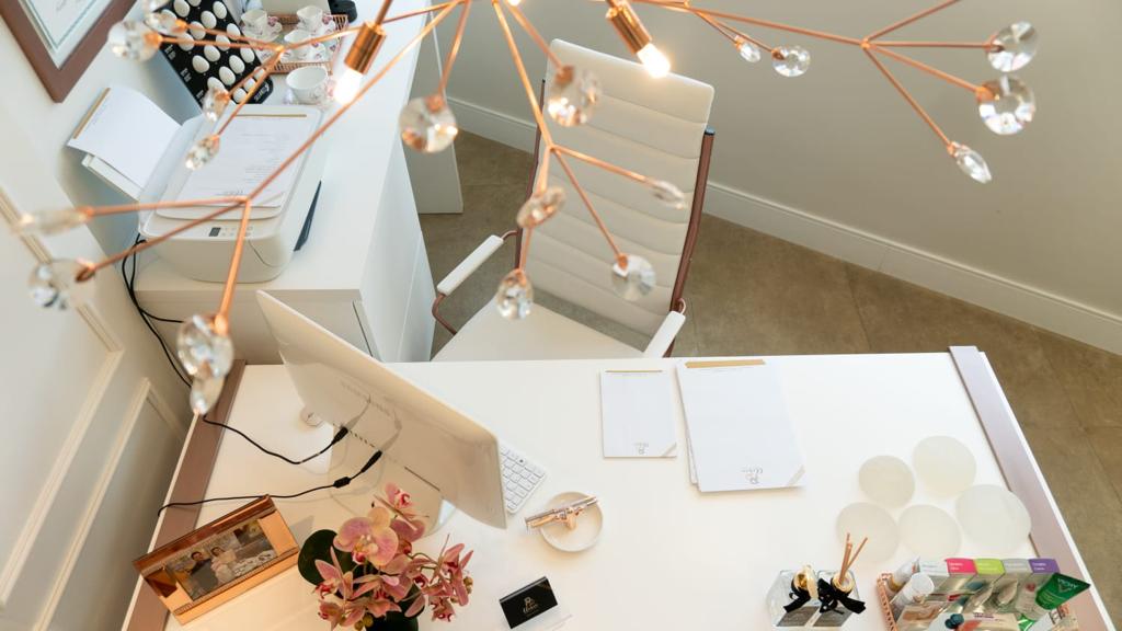 Mesa de atendimento vista de cima, com orquídeas, blocos de papel timbrado e implantes de demonstração
